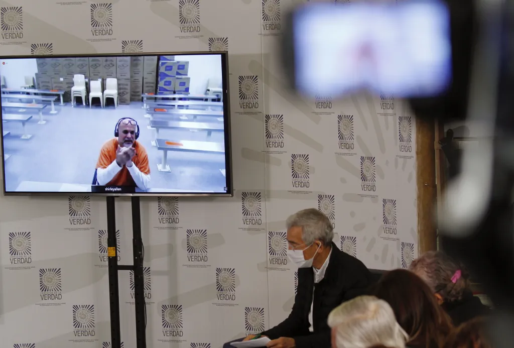 Fotografía de archivo del presidente de la Comisión de la Verdad, el sacerdote Francisco de Roux (d), oye la intervención en videollamada del exlíder paramilitar Salvatore Mancuso (pantalla), en Bogotá (Colombia). Foto: EFE/ Juan Diego López