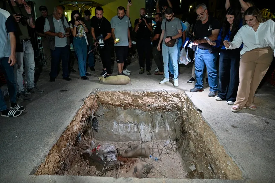 Varias personas observan el cráter causado por la explosión de un dispositivo de comunicación en el estacionamiento del Centro Médico de la Universidad Americana de Beirut. EFE/EPA/Wael Hamzeh