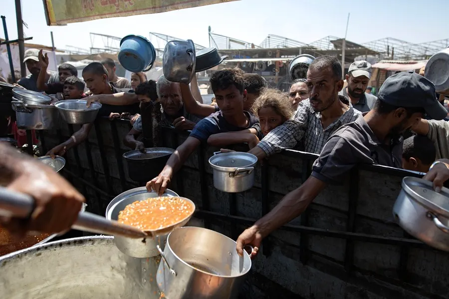 Los palestinos desplazados internos reciben alimentos donados por una organización benéfica en el campamento de Khan Younis, al sur de la Franja de Gaza, que según la UNRWA. Foto: EFE/EPA/Haitham Imad