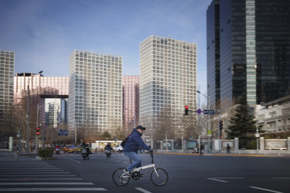 Un hombre pasa por un cruce, ante edificios de oficinas del Distrito Central de Negocios en Beijing, China, el lunes 3 de marzo de 2025. Foto: AP Foto/Vincent Thian