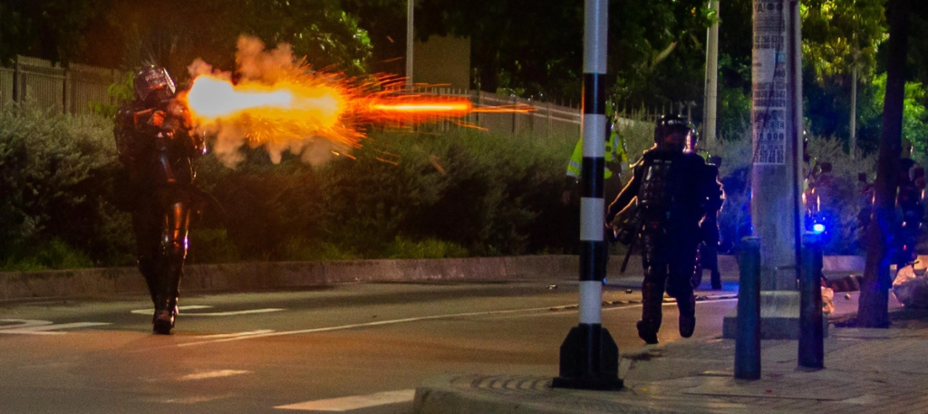 Un policía dispara, tratando de dispersar a manifestantes, en la protesta local por muerte de un abogado en Barranquilla. Foto: VANEXA ROMERO – El Tiempo