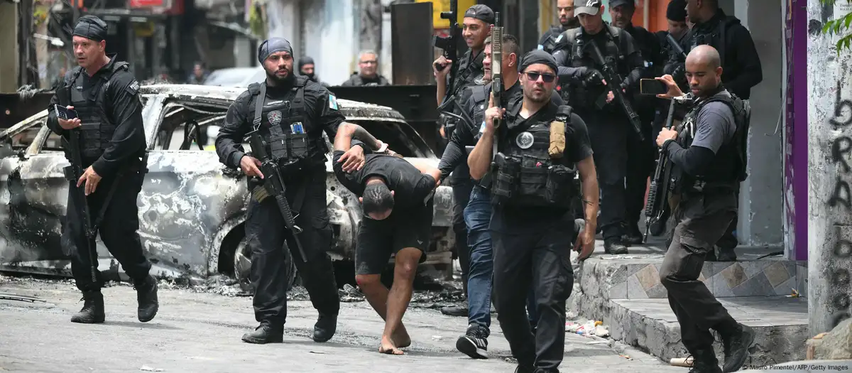 Agentes de policía escoltan a un sospechoso arrestado durante la operación fuera de la favela Vila Cruzeiro, en el complejo Penha, Río de Janeiro (28.10.2025) Foto: Mauro Pimentel/AFP/Getty Images