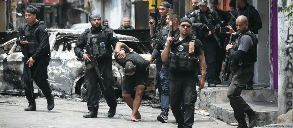 Agentes de policía escoltan a un sospechoso arrestado durante la operación fuera de la favela Vila Cruzeiro, en el complejo Penha, Río de Janeiro (28.10.2025) Foto: Mauro Pimentel/AFP/Getty Images